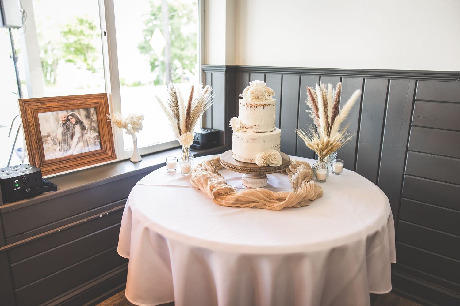 Wedding decor details including framed photos and floral arrangements on white tablecloths.