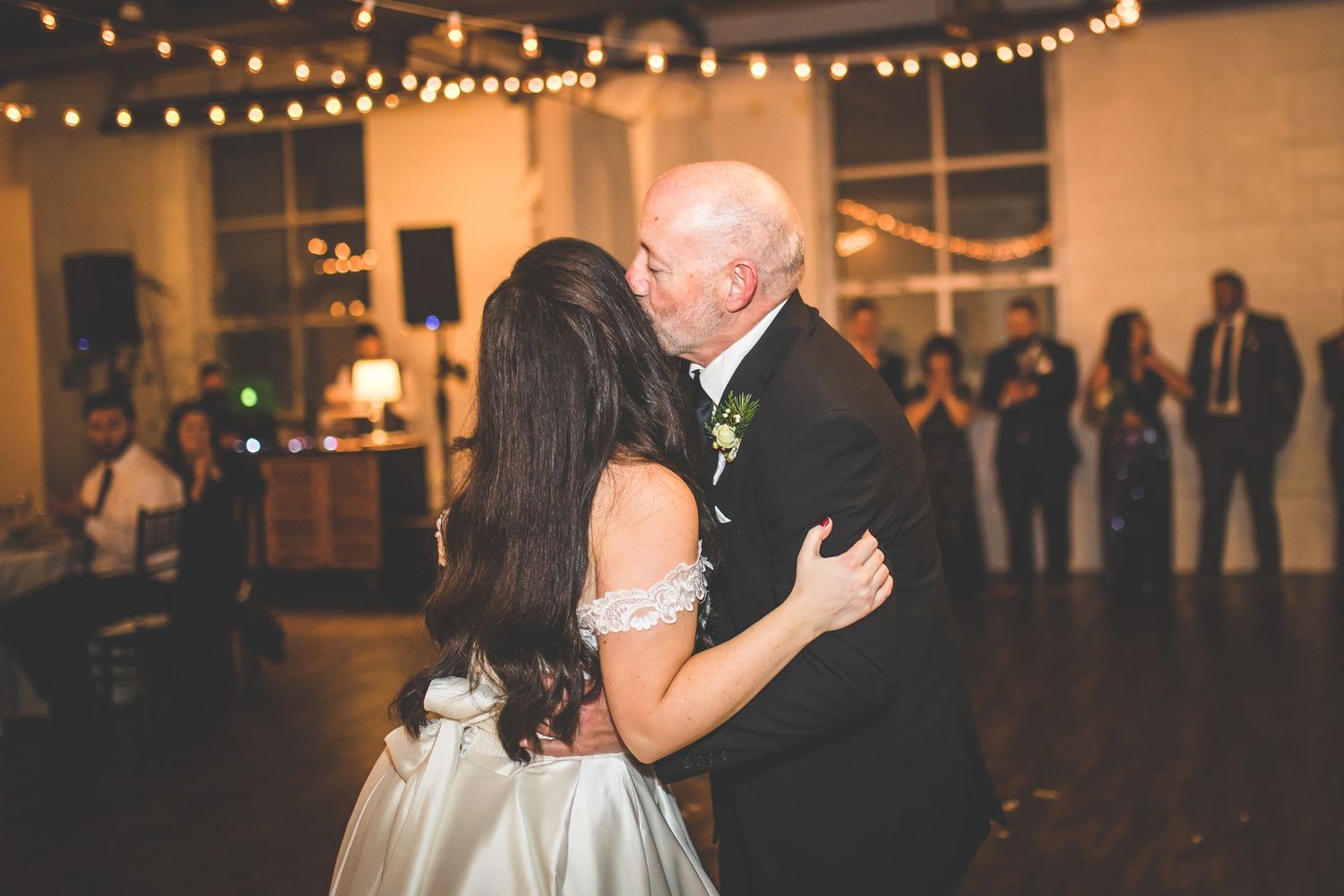 Wedding reception dance floor with string lights and guests dancing in an elegant indoor venue.