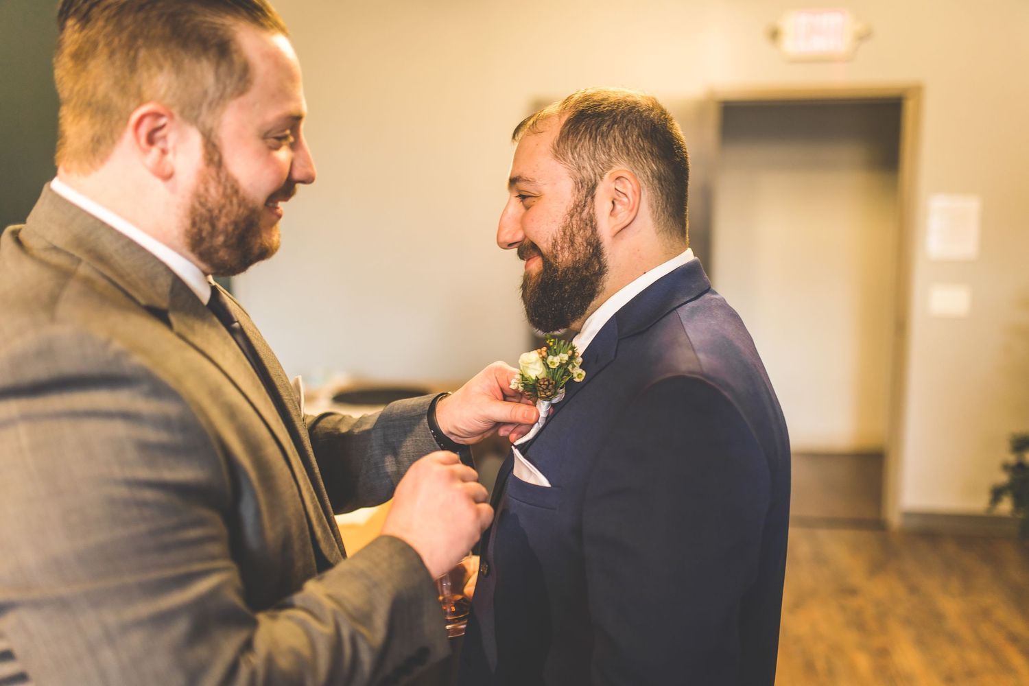 Groomsmen share a lighthearted moment while adjusting their ties and suits before the wedding ceremony.