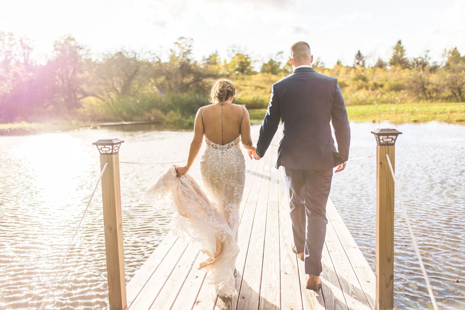 A couple shares a romantic moment on a wooden dock by a lake during golden hour.