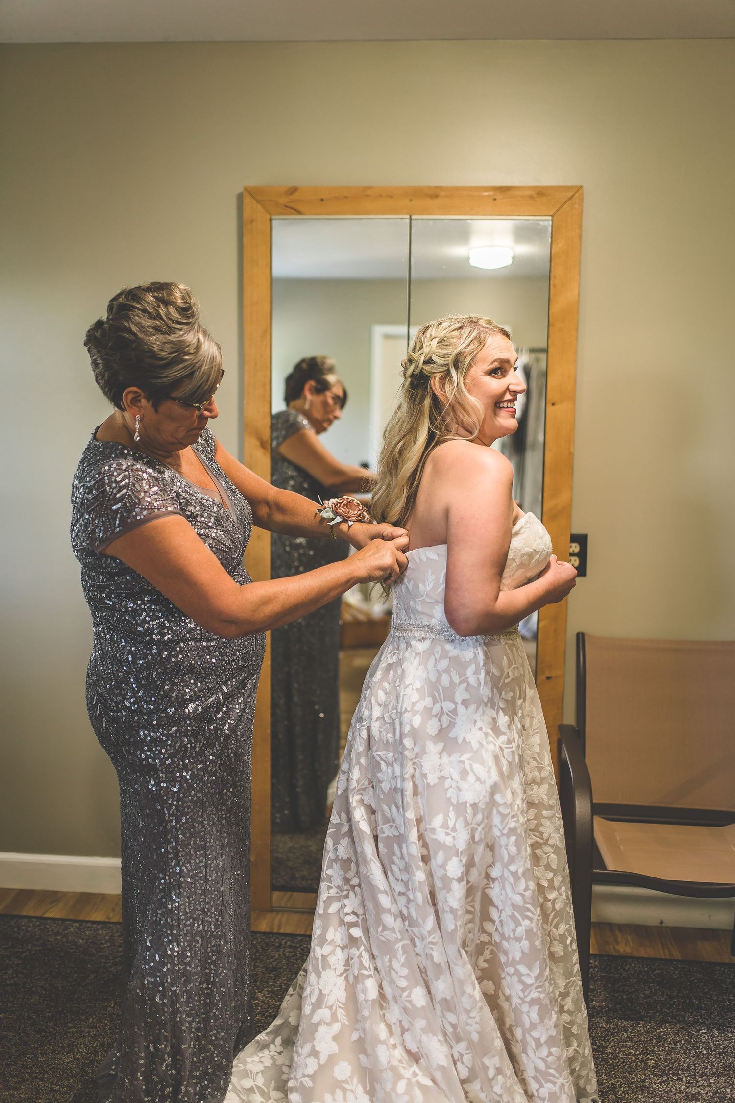 Wedding dress preparation scene showing final adjustments in a dressing room with mirrors.