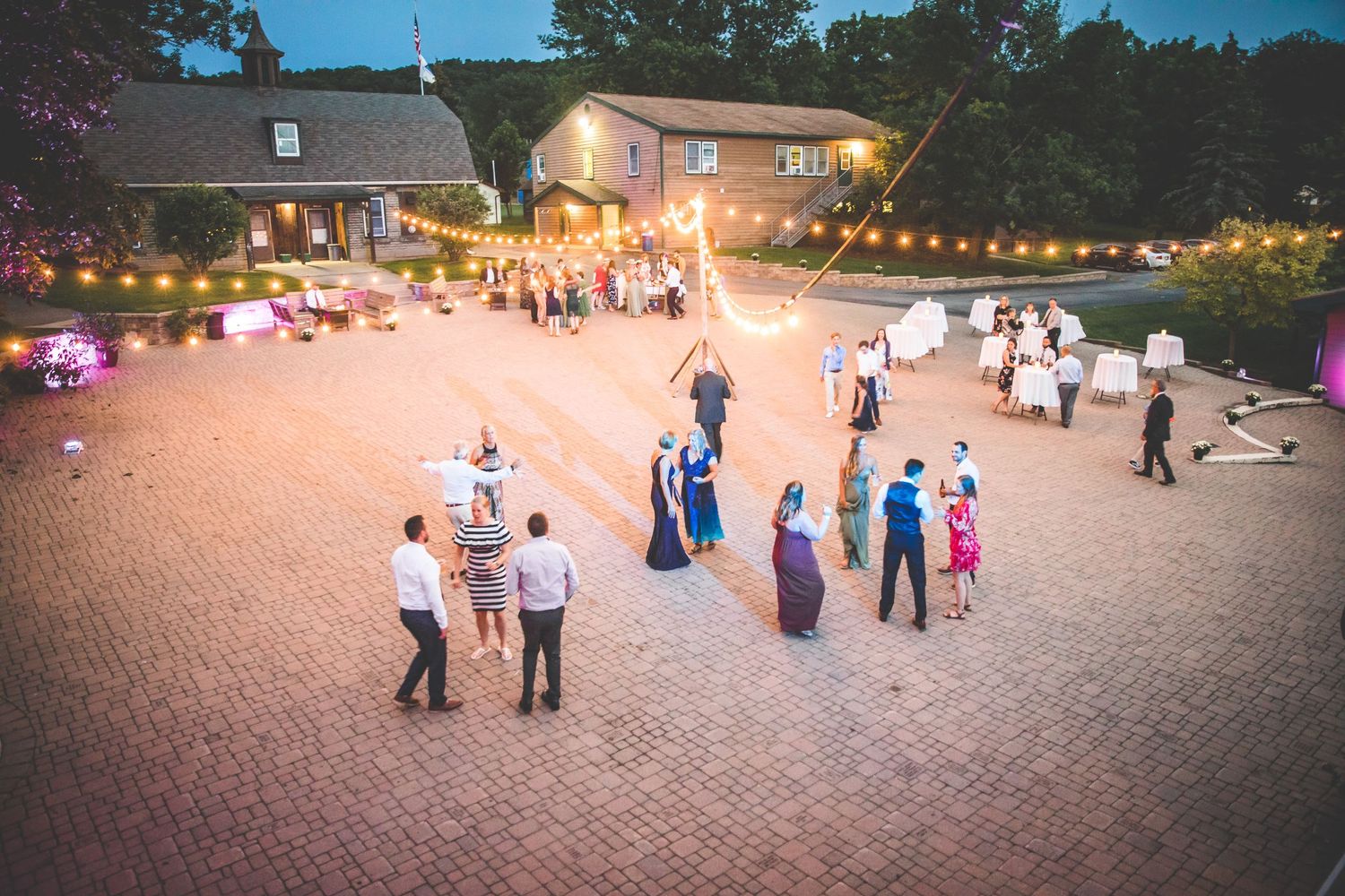 Guests mingle on a brick patio during an outdoor wedding reception.