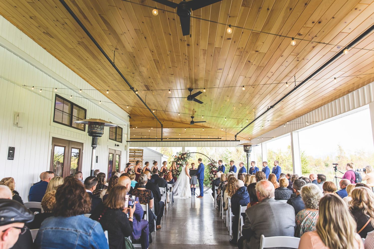 Wedding reception venue with wooden ceiling and natural lighting filled with guests.