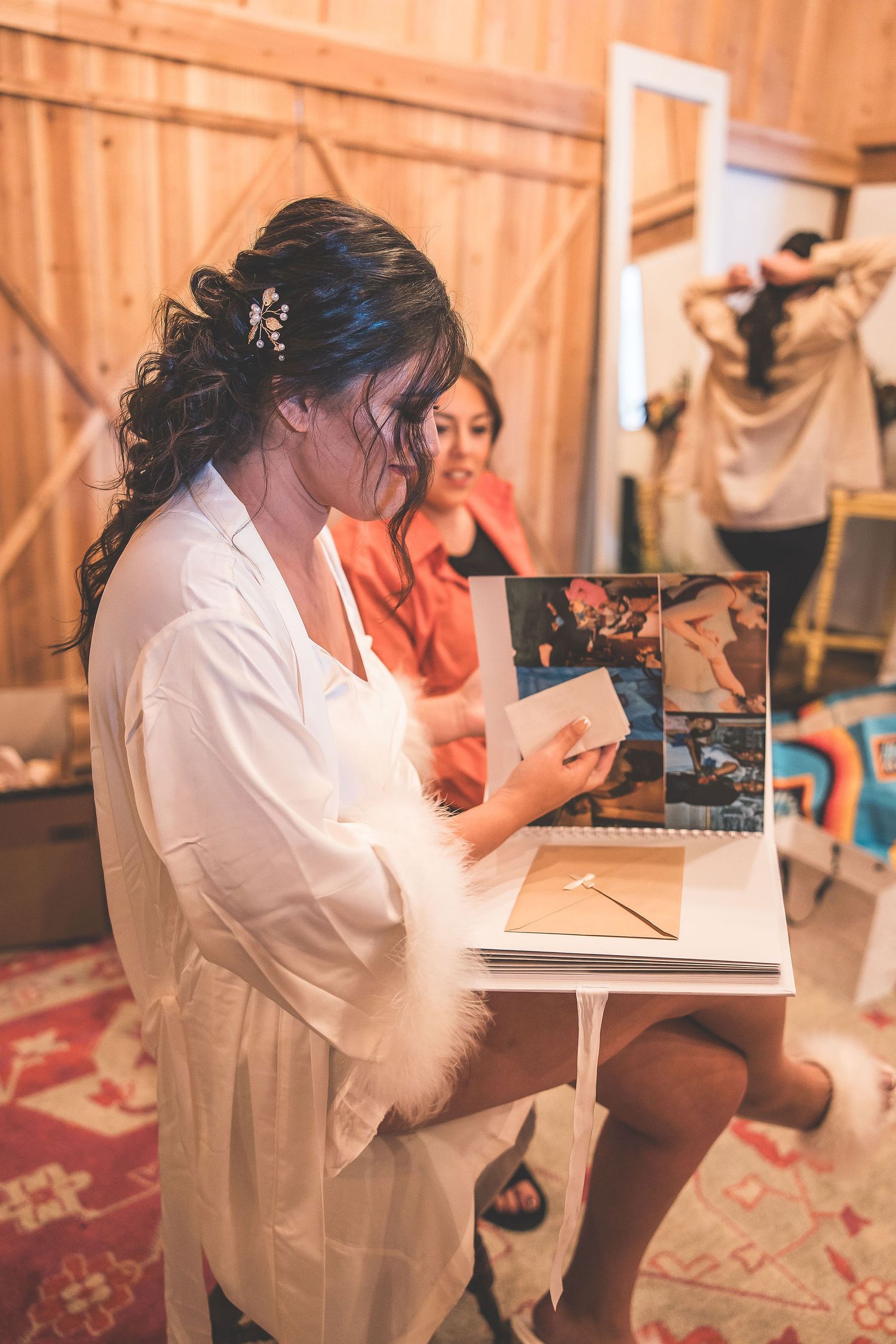 Someone in a white robe looks through a photo album during wedding preparations.