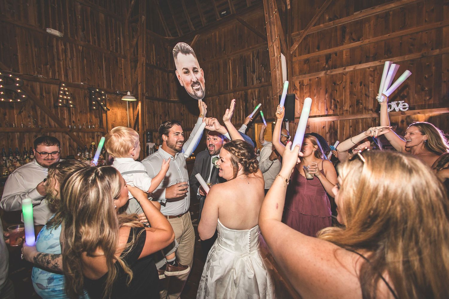 Guests dancing and celebrating on the dance floor at a rustic barn wedding reception.