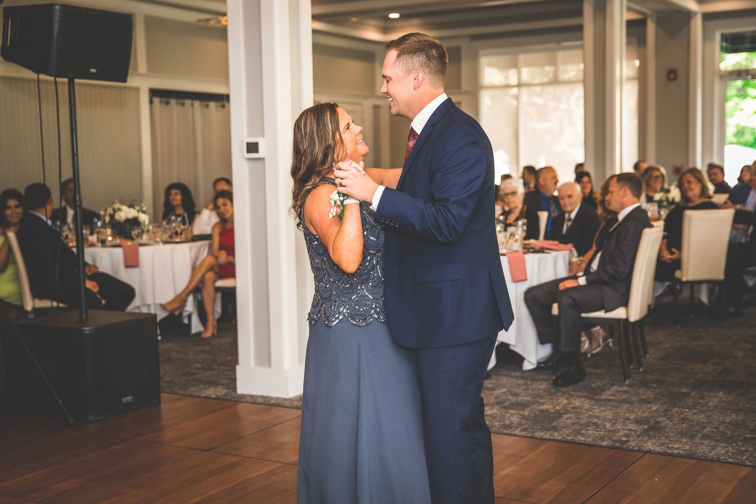 Panoramic view of wedding reception dance floor with couple surrounded by seated guests.
