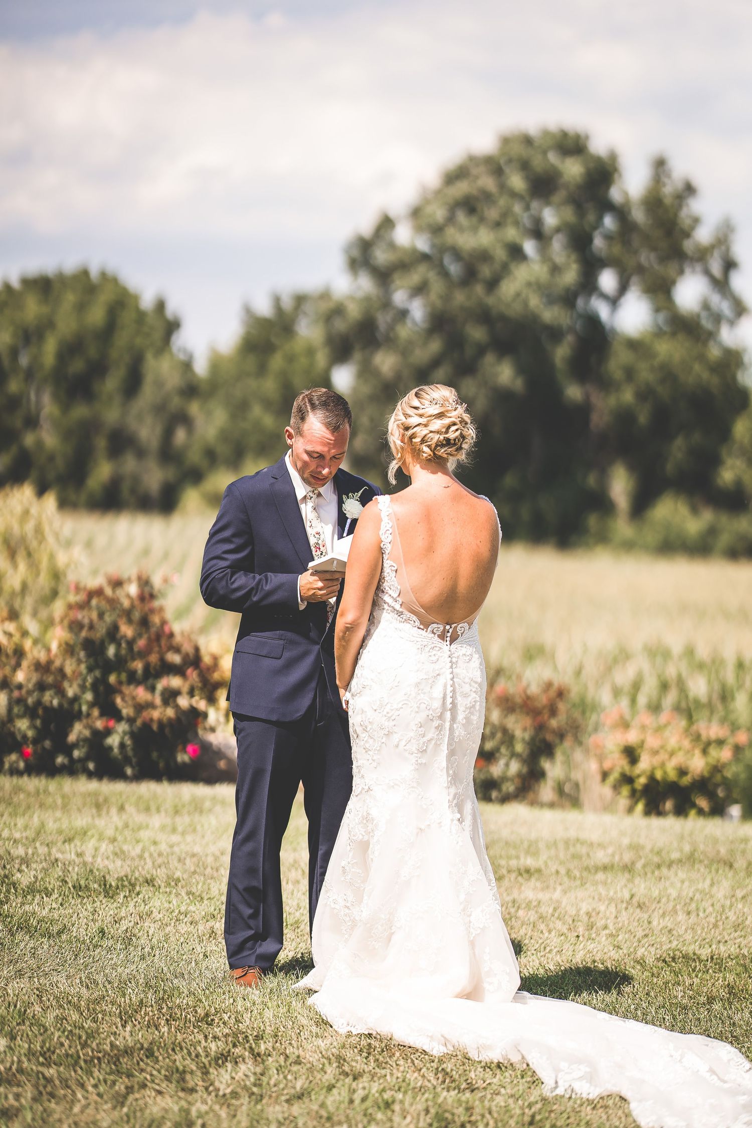 A couple shares an intimate moment during their first look in a sunlit garden setting.