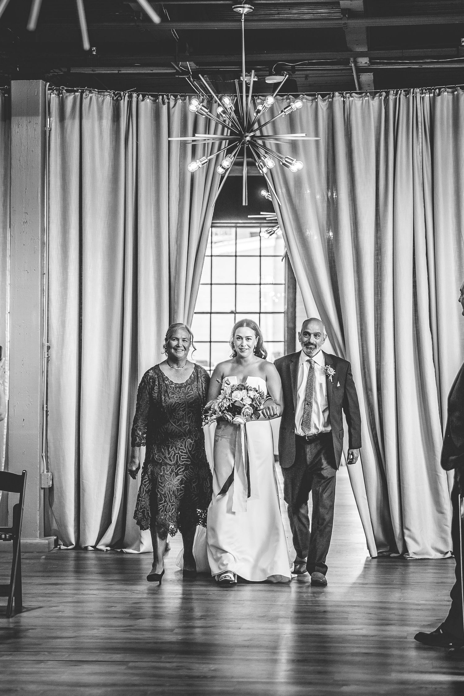 Dramatic black and white shot of wedding processional in an elegant venue.
