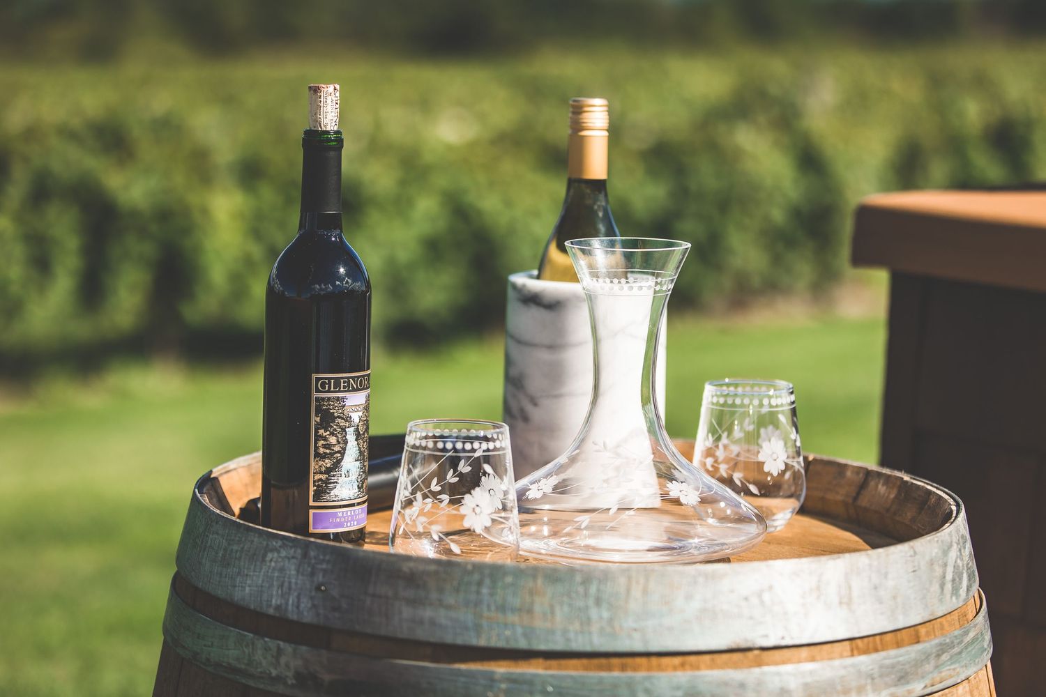 Rustic outdoor bar setup with wine barrels and glassware.
