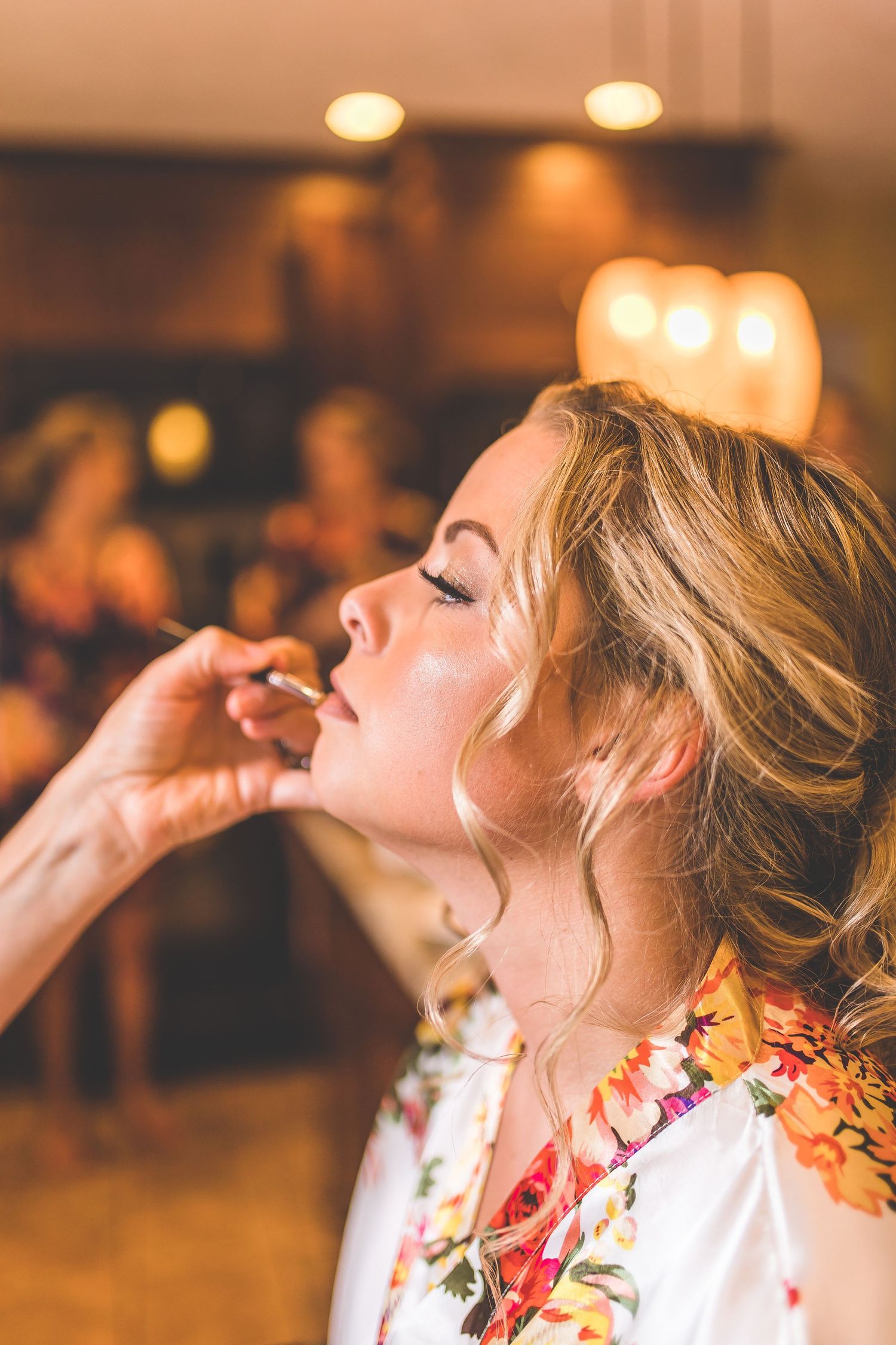 Wedding party getting ready in floral robes with warm lighting.