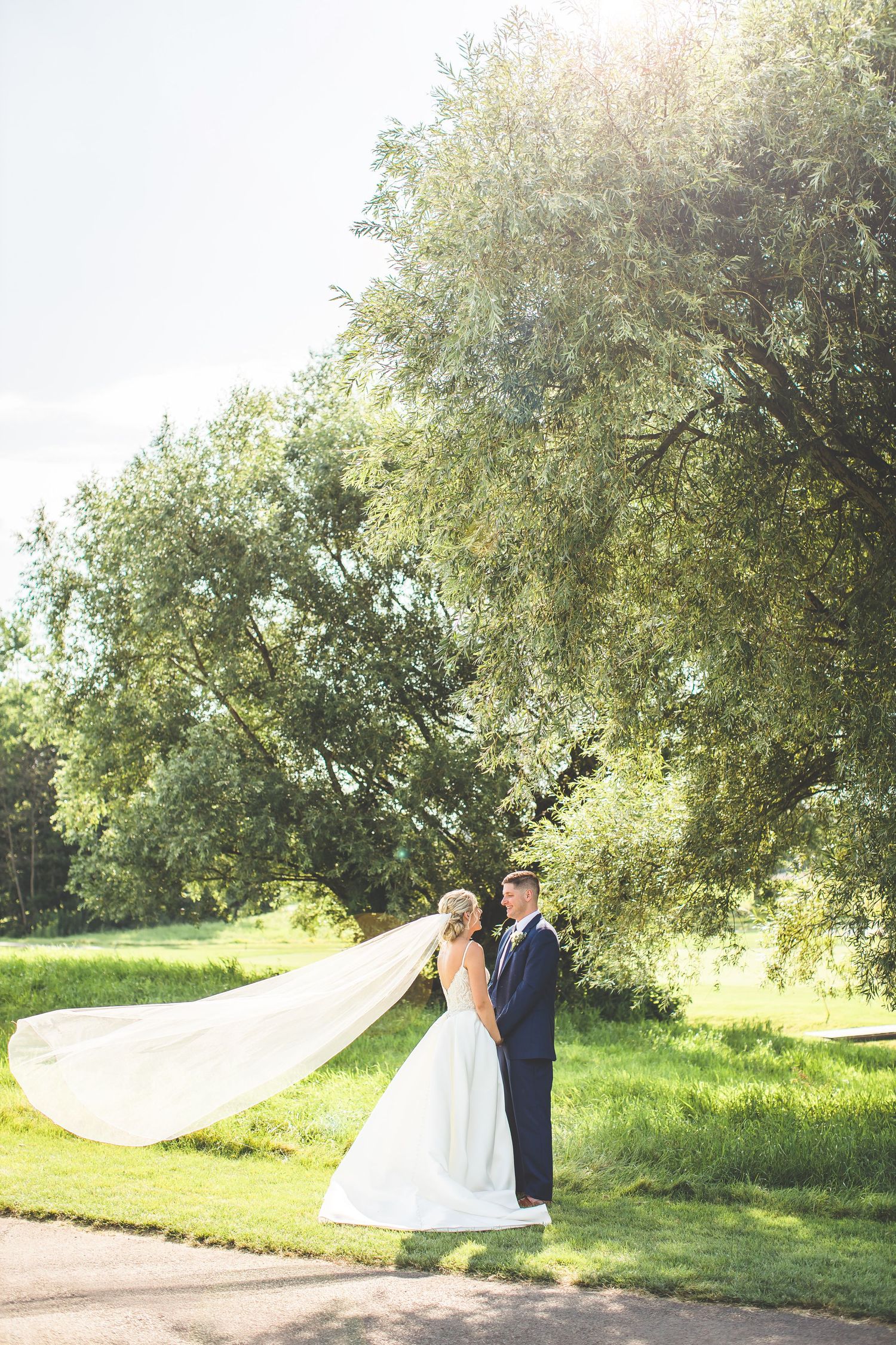 Romantic wedding photos with flowing veil against natural outdoor backdrop.