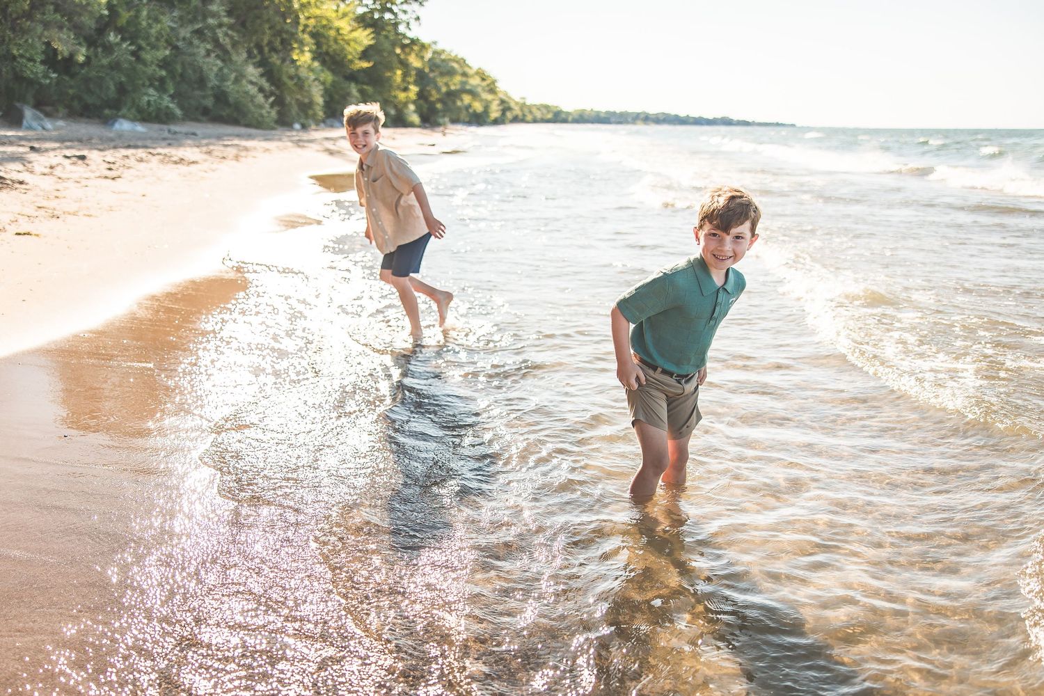 People enjoying a sunny day playing in the waves at a scenic beach.