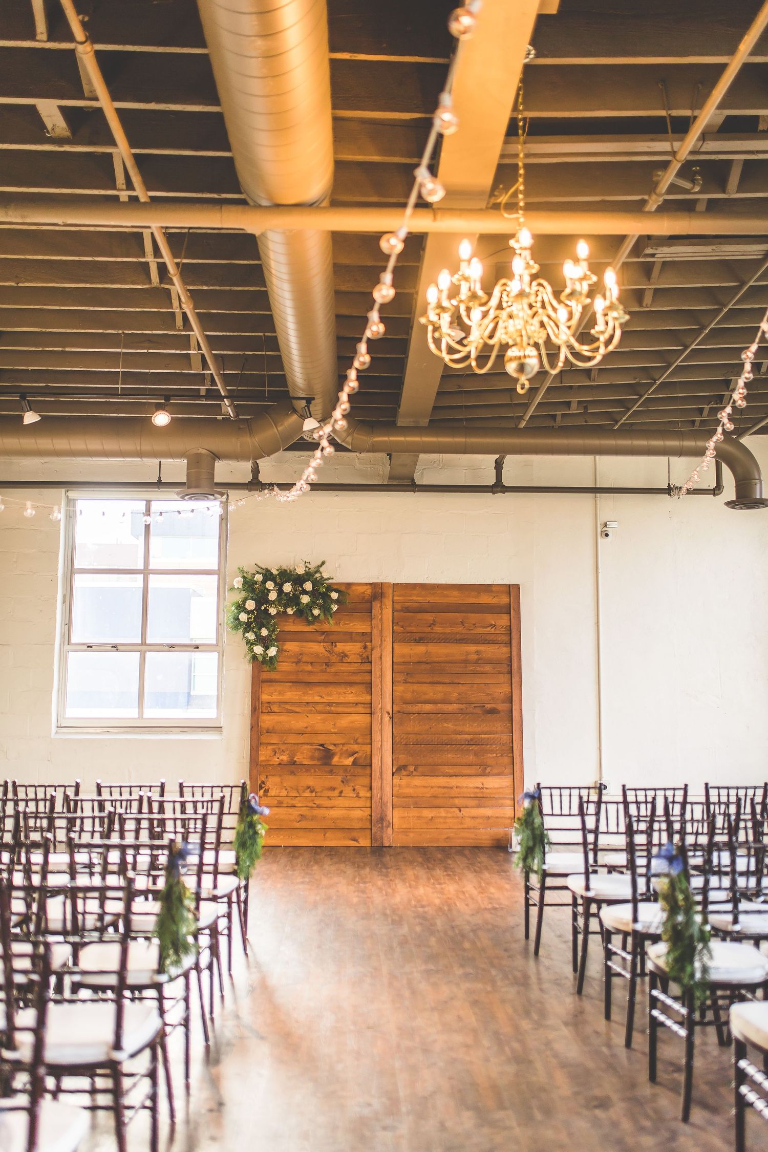 Empty wedding ceremony venue with wooden chairs and string lights.