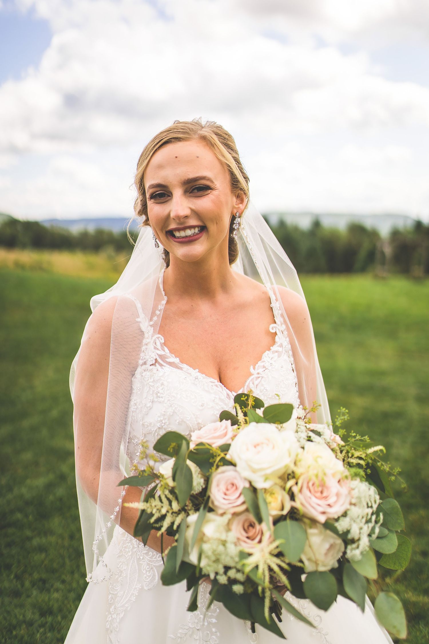 Close-up of bridal bouquet with pink and white roses against green outdoor backdrop.