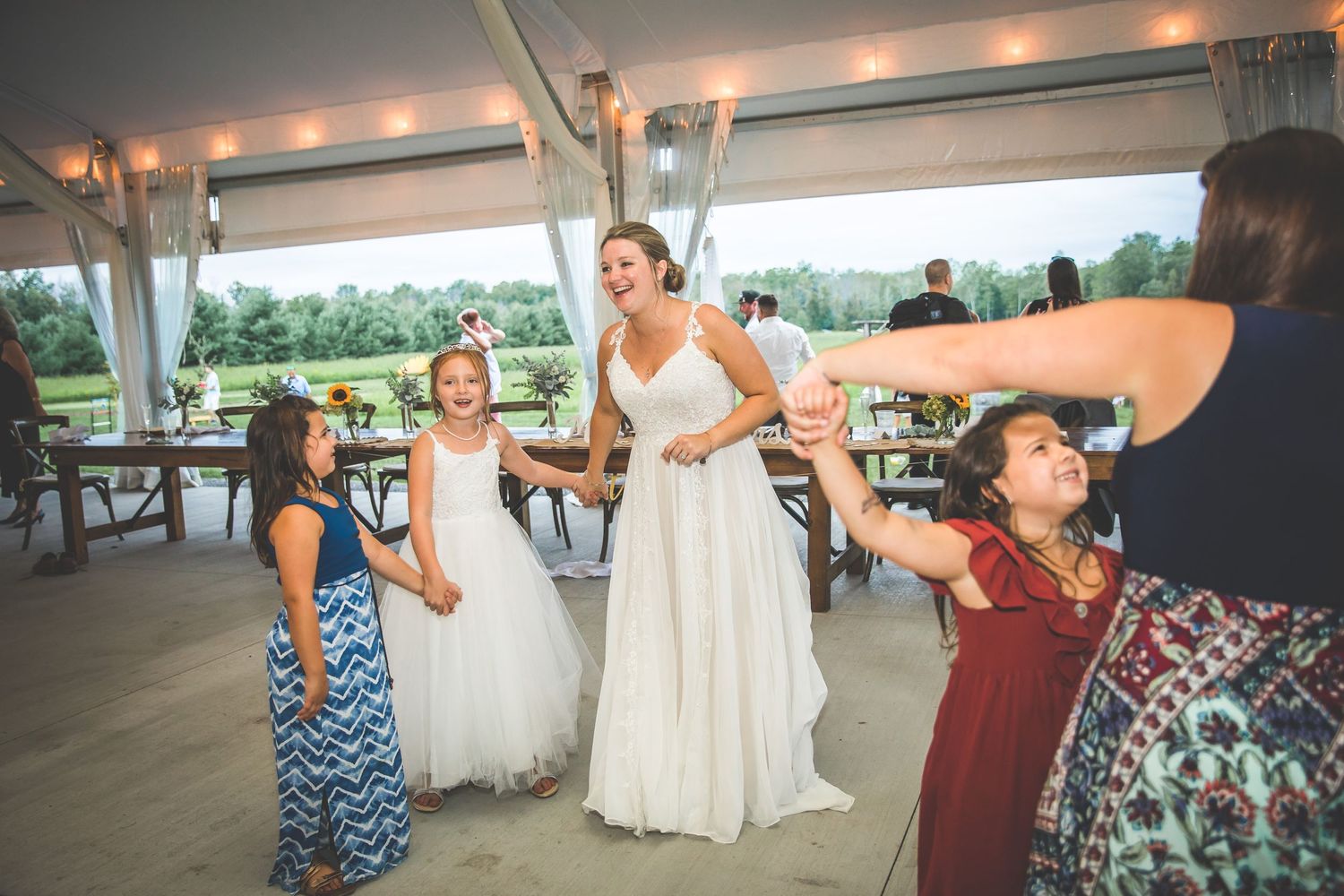 Wedding guests dancing and celebrating on the dance floor under a tent.