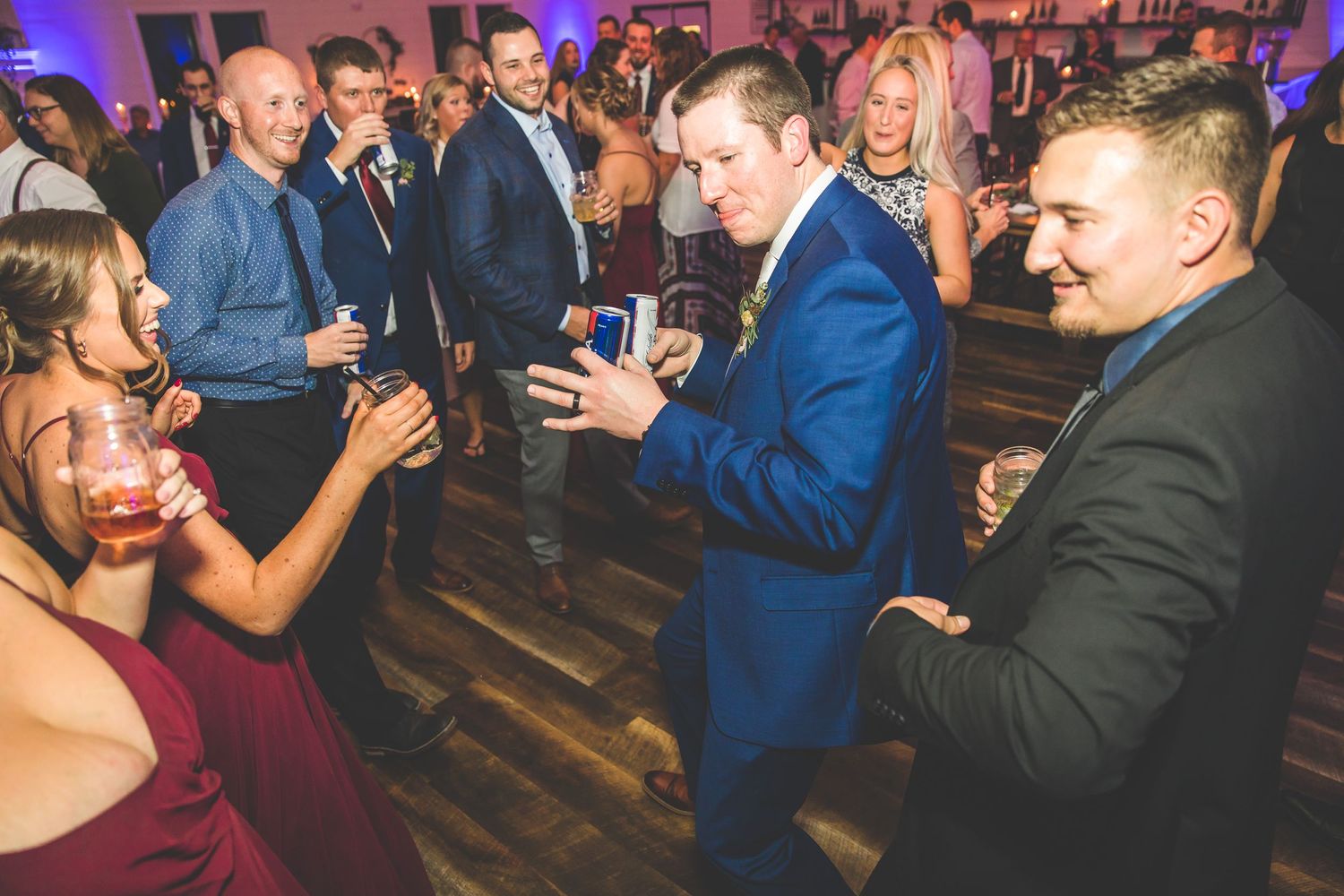 Panoramic view of wedding guests dancing and mingling at an indoor reception.