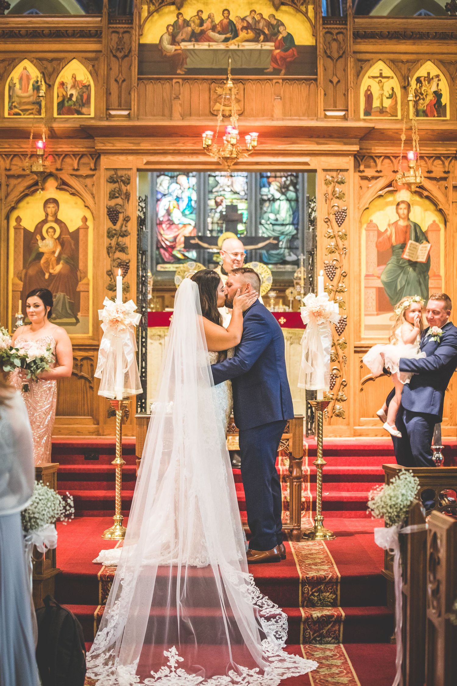 Wedding ceremony in progress with beautiful religious iconography and decorative altar backdrop.