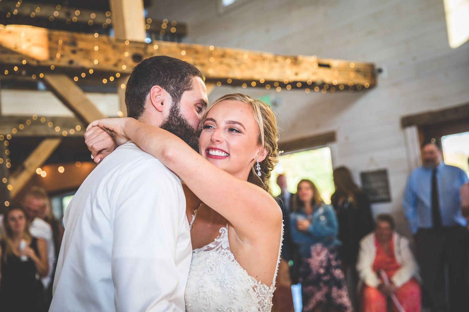 Close-up shot of a joyful couple dancing at their wedding reception under string lights.