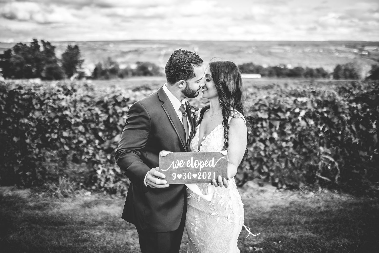 Black and white wedding portraits taken in a scenic vineyard setting.
