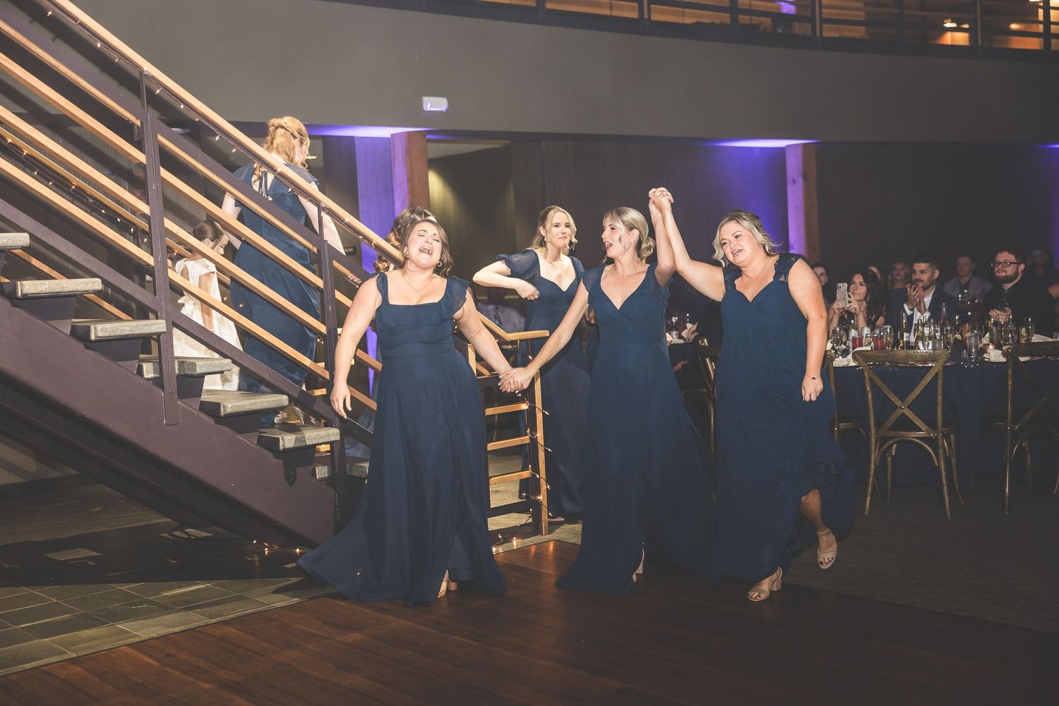 Wedding reception venue with purple uplighting and wooden staircase details.