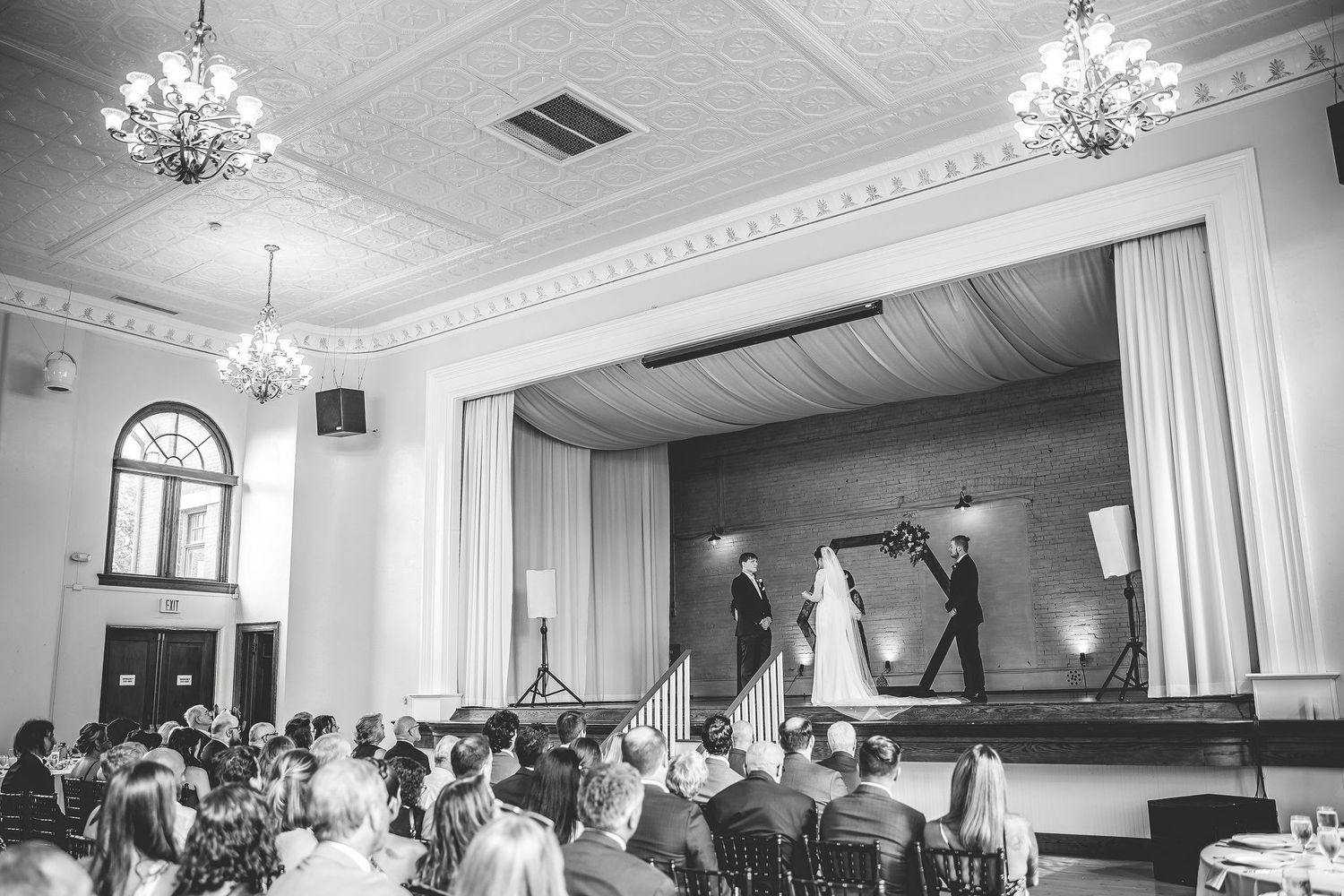 Panoramic view of elegant wedding venue with crystal chandeliers and white decor.
