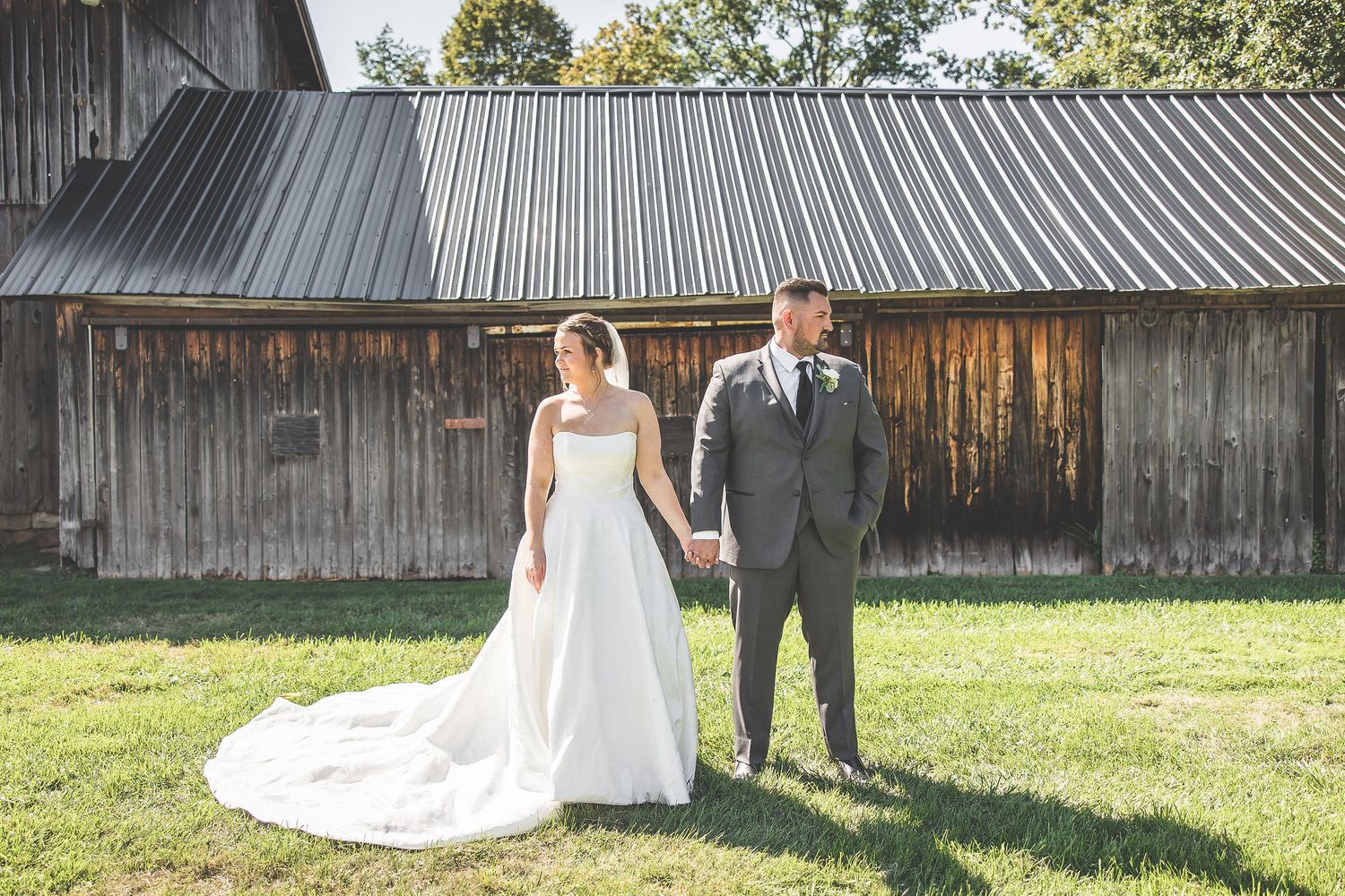 Wedding couple poses in various shots with a rustic barn and metal roof in the background.