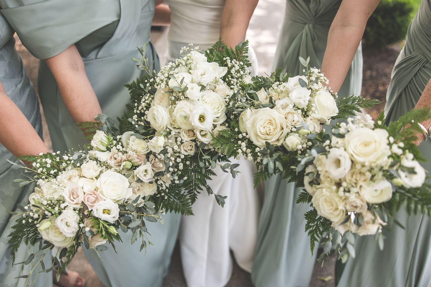 Close-up of elegant white and green wedding bouquets held by bridesmaids.