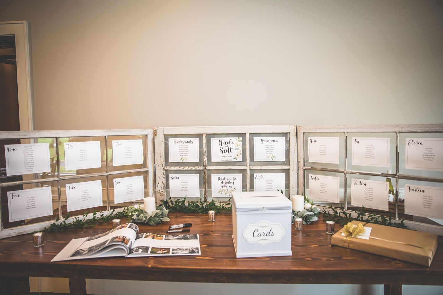 Wedding photo display with wooden frames arranged on dark wooden table.