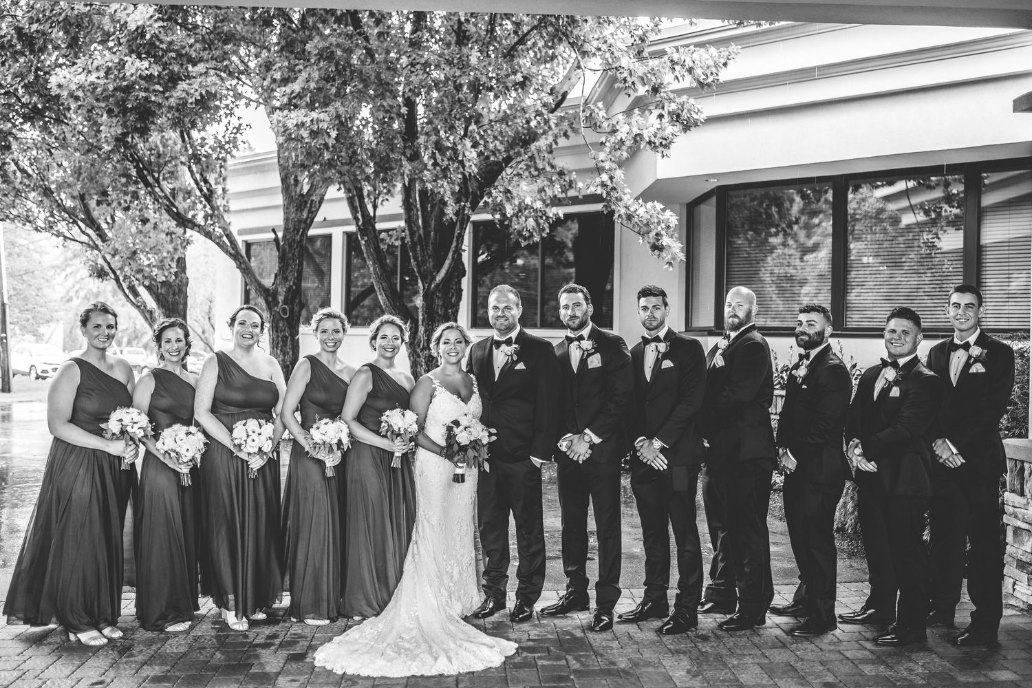 Wedding party in navy and black formal attire lined up for group photos.