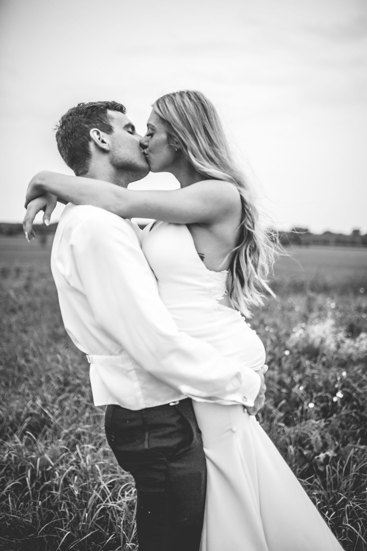 Black and white portrait of a romantic moment between newlyweds in a field.