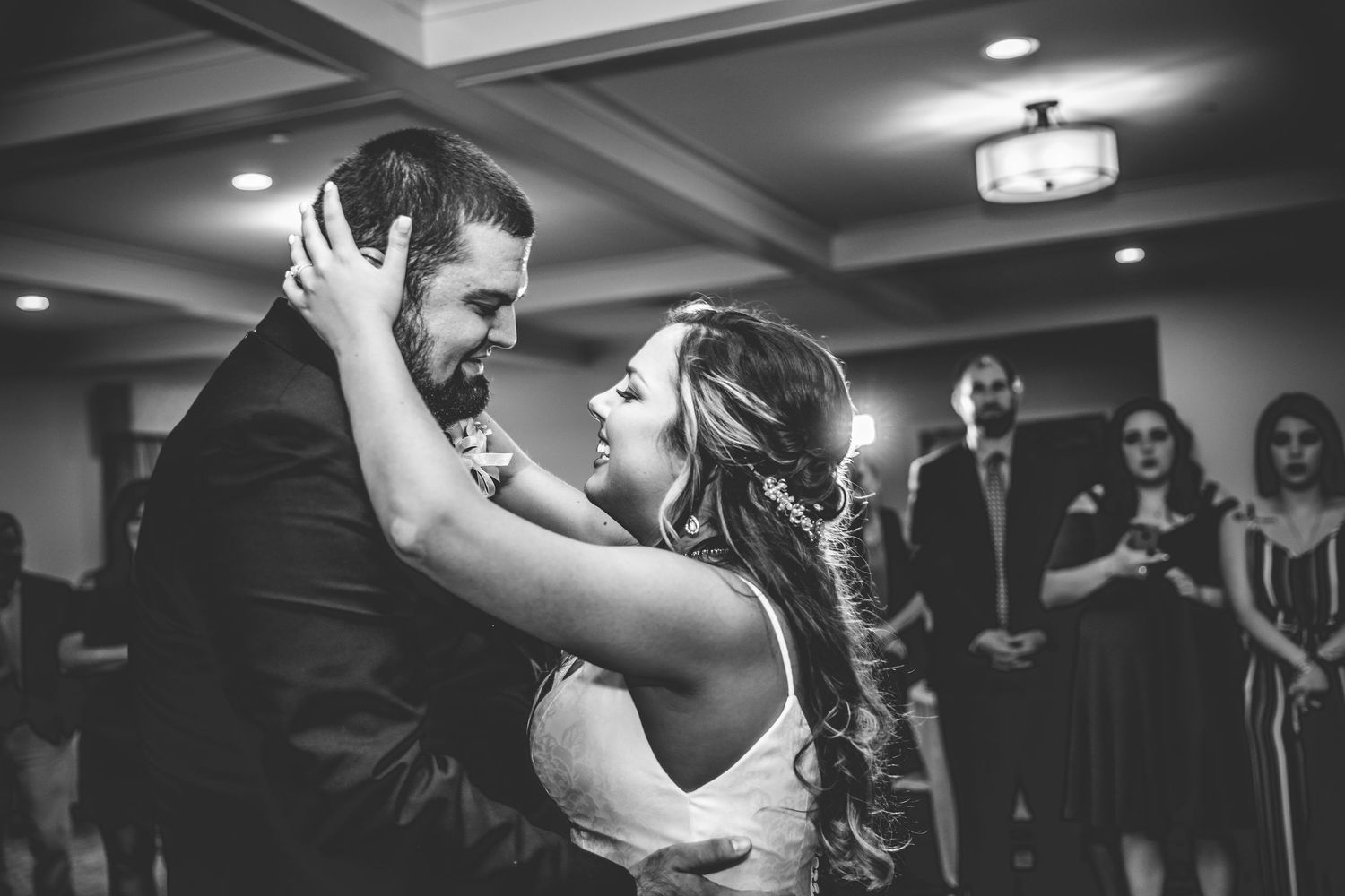 Black and white reception photo of couples dancing under dim lighting.