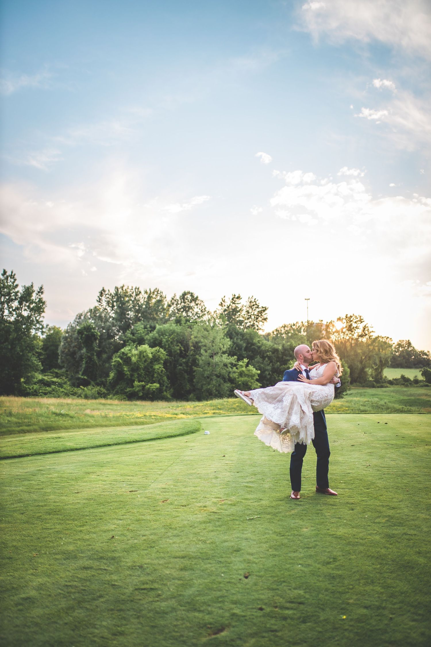 Romantic sunset photos of newlyweds on a lush green golf course.
