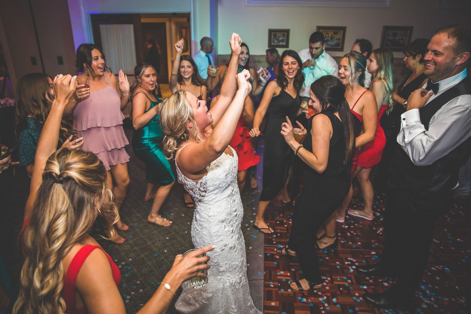Wedding guests dancing and celebrating with confetti on the dance floor.