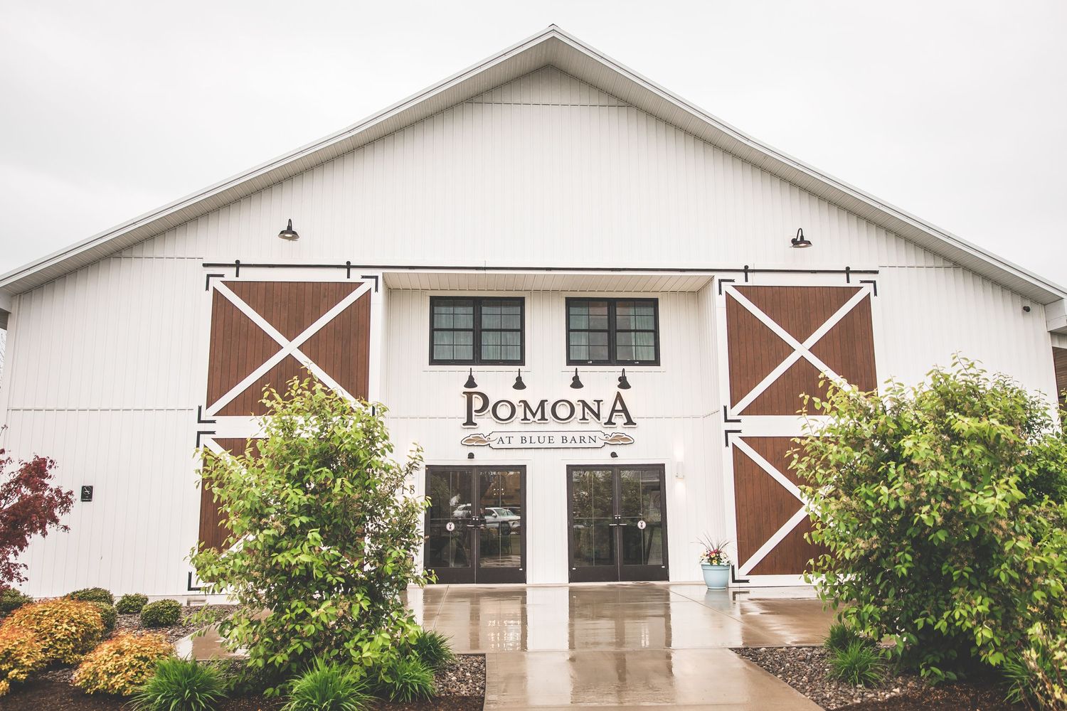 The exterior of Pomona wedding venue featuring white barn doors with rustic brown accents.