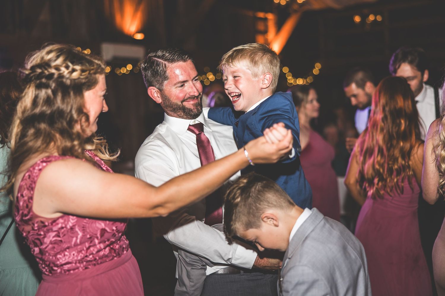Lively dance floor at a wedding reception with guests celebrating in formal attire.