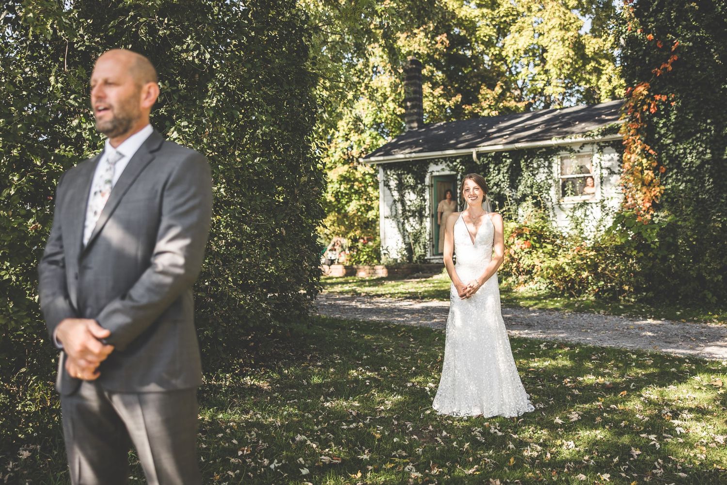 A first look wedding moment captured in a garden setting with the couple standing apart in elegant attire.