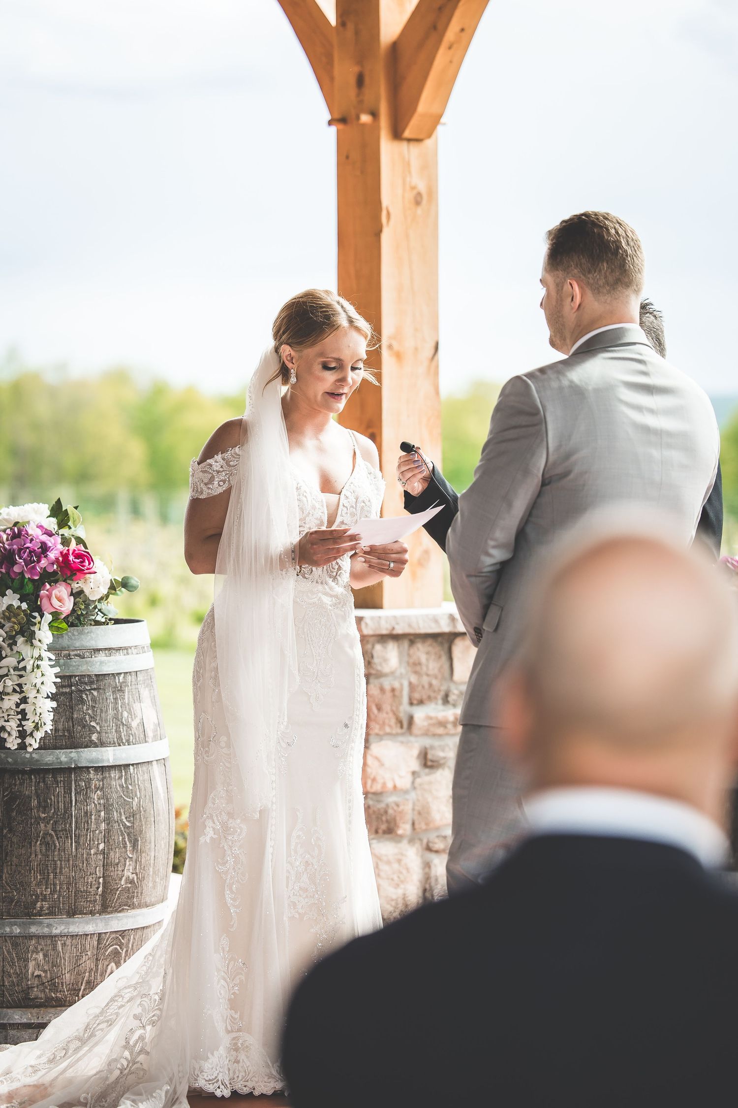 Couple sharing emotional moment during wedding ceremony next to rustic wine barrel decor.