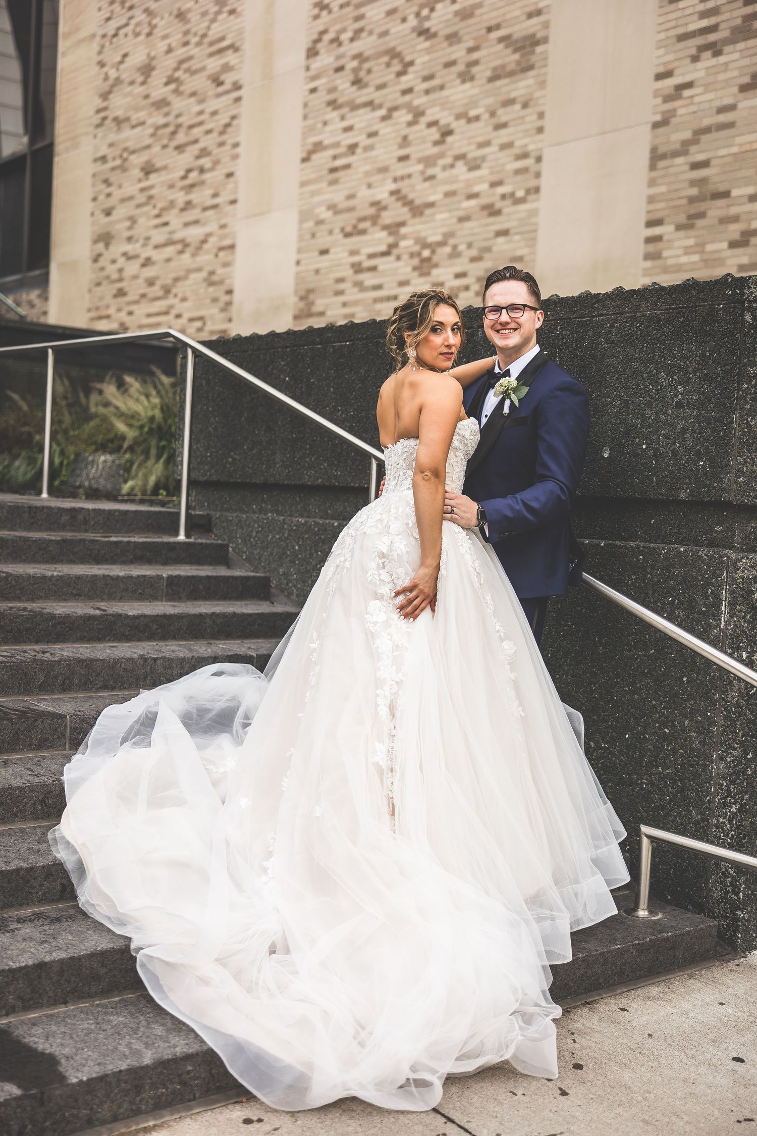 Wedding couple shares intimate moments on urban steps with textured wall backdrop.