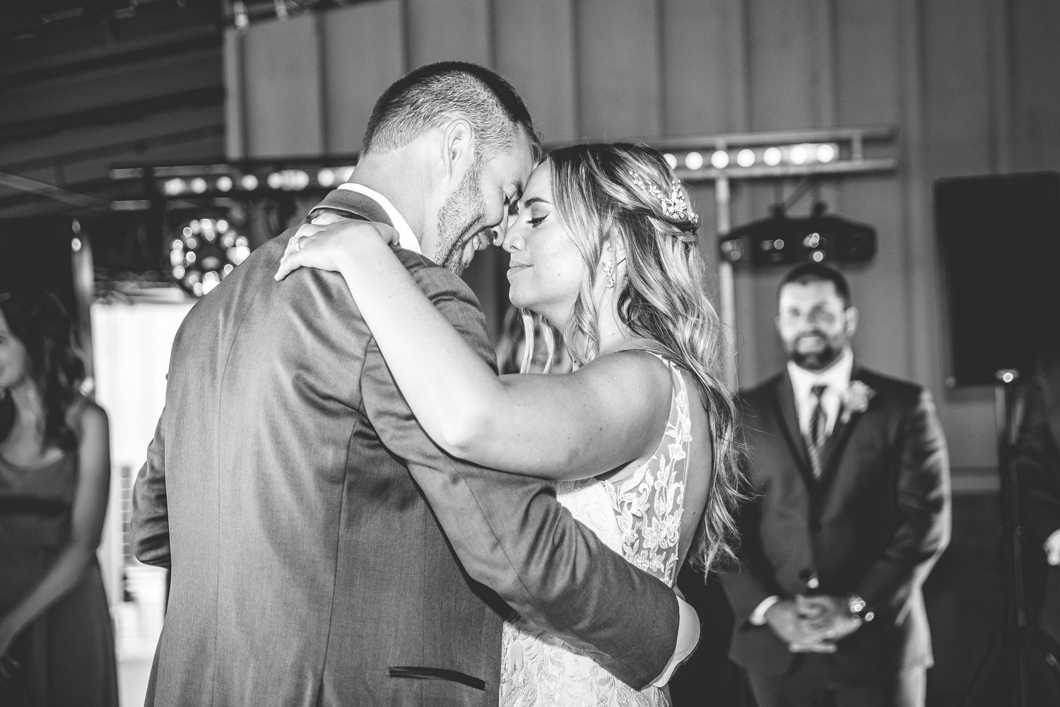 A couple shares an intimate first dance at their wedding reception while guests look on.