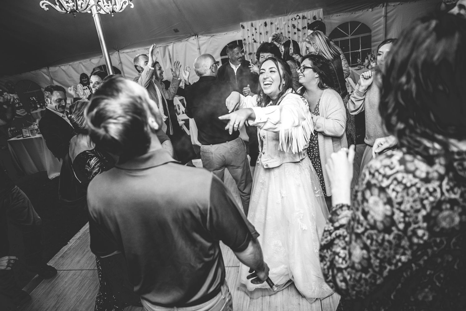 Wedding guests dancing and celebrating on a dimly lit dance floor.