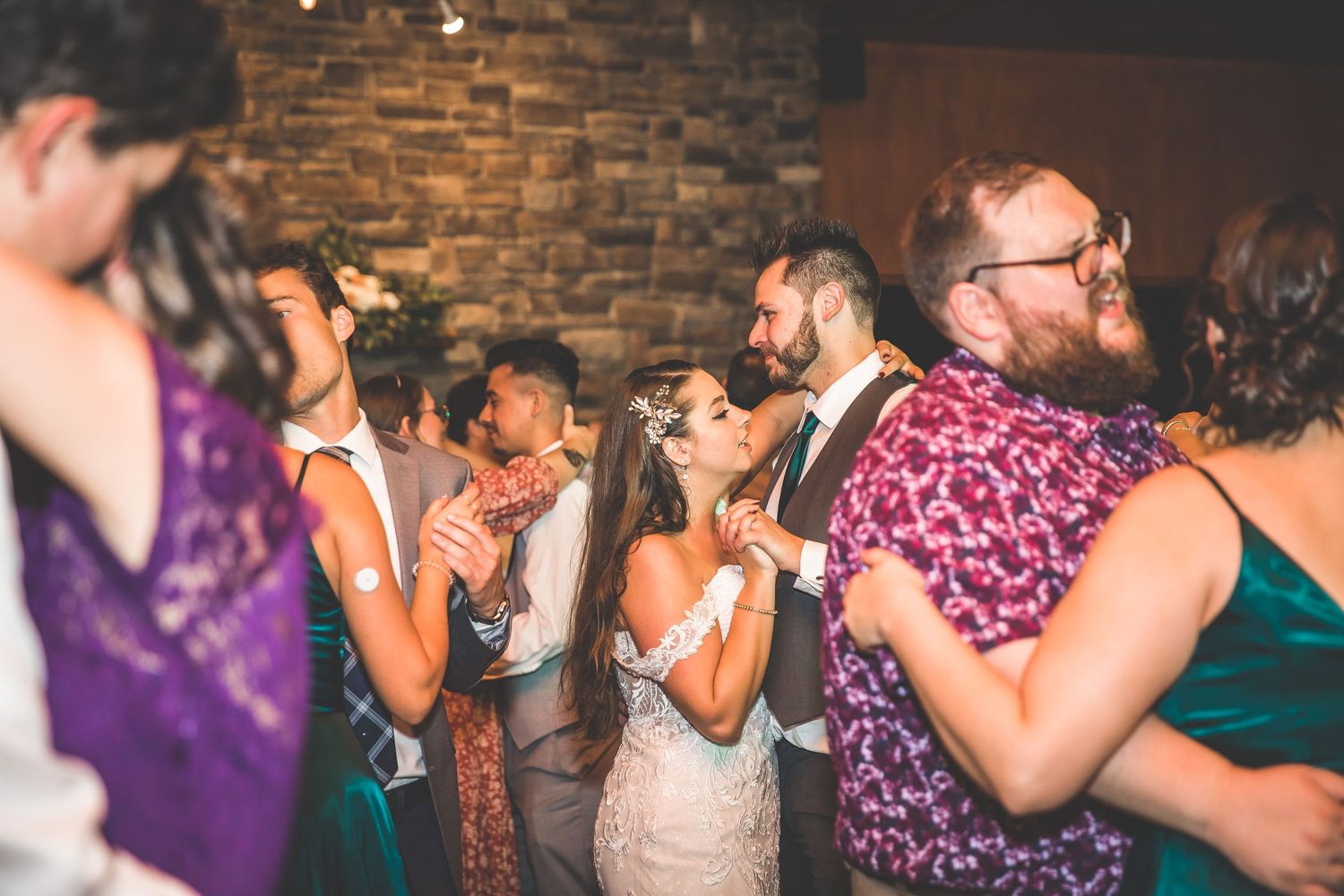 Wedding guests dancing and celebrating at an evening reception.