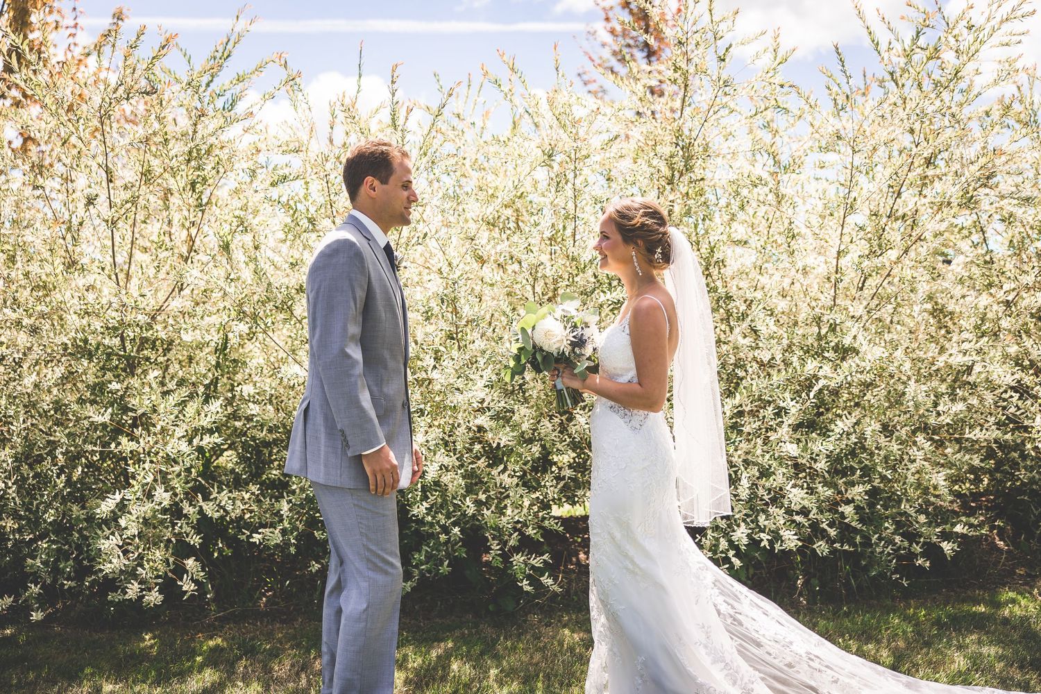 Newlyweds exchange loving glances in an orchard setting.