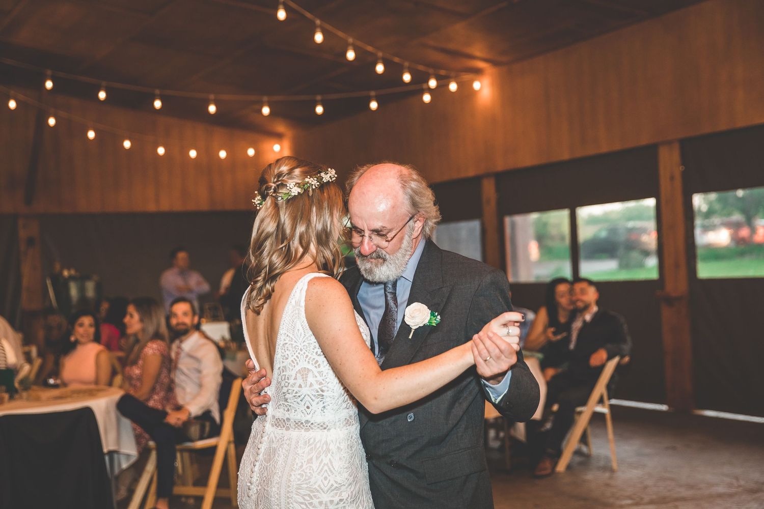 Couples share intimate dances during a wedding reception under warm string lights.