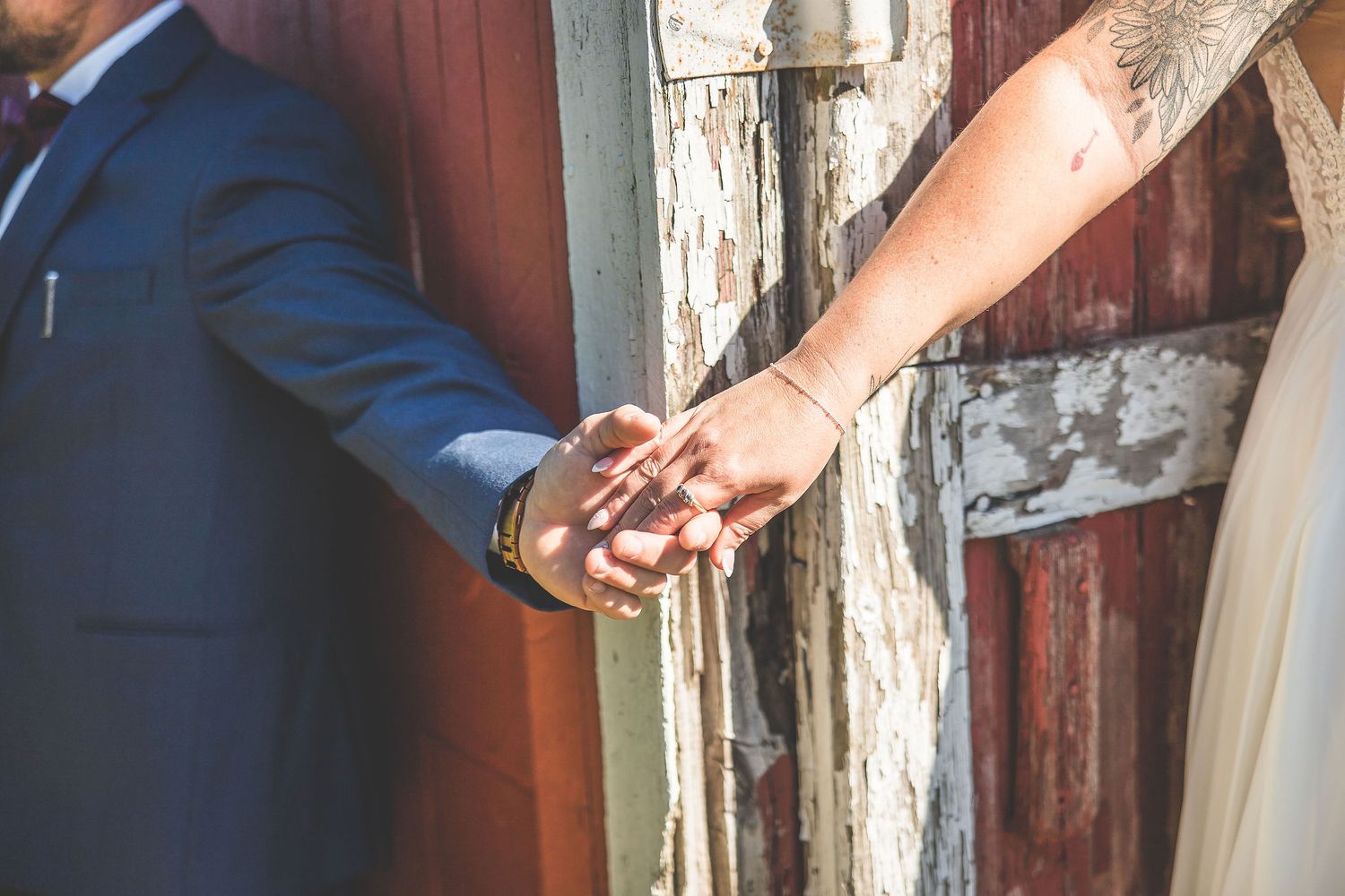 Close-up details of couple's tender moment against weathered barn door.