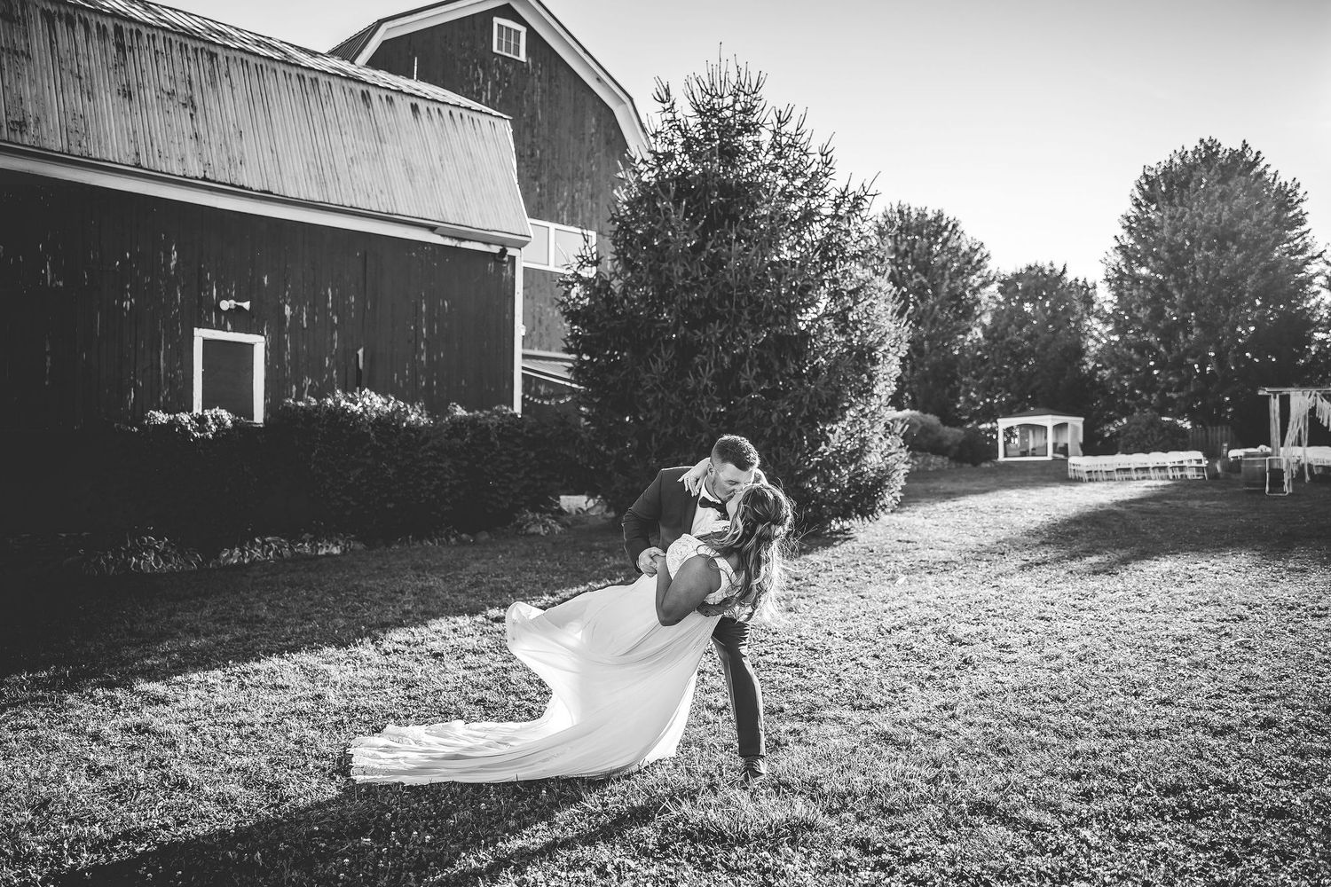 Black and white landscape view of rustic barn wedding venue with rolling hills.