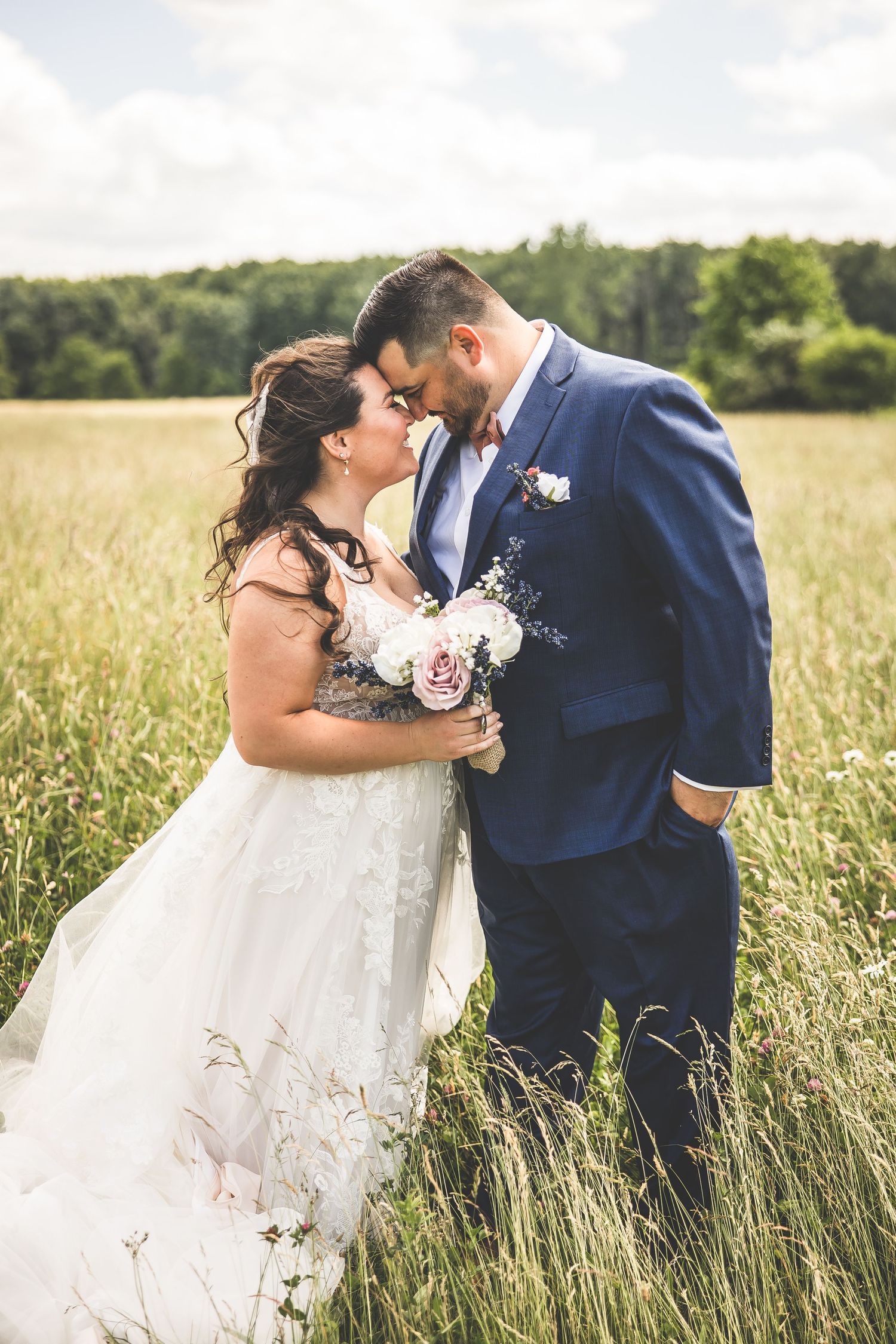 Romantic couple embraces in tall grass field during golden hour wedding photoshoot.