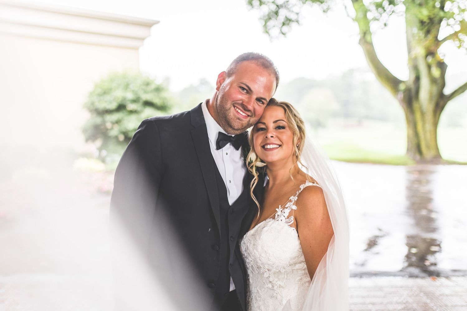 Romantic wedding portrait captured outdoors on a rainy day.