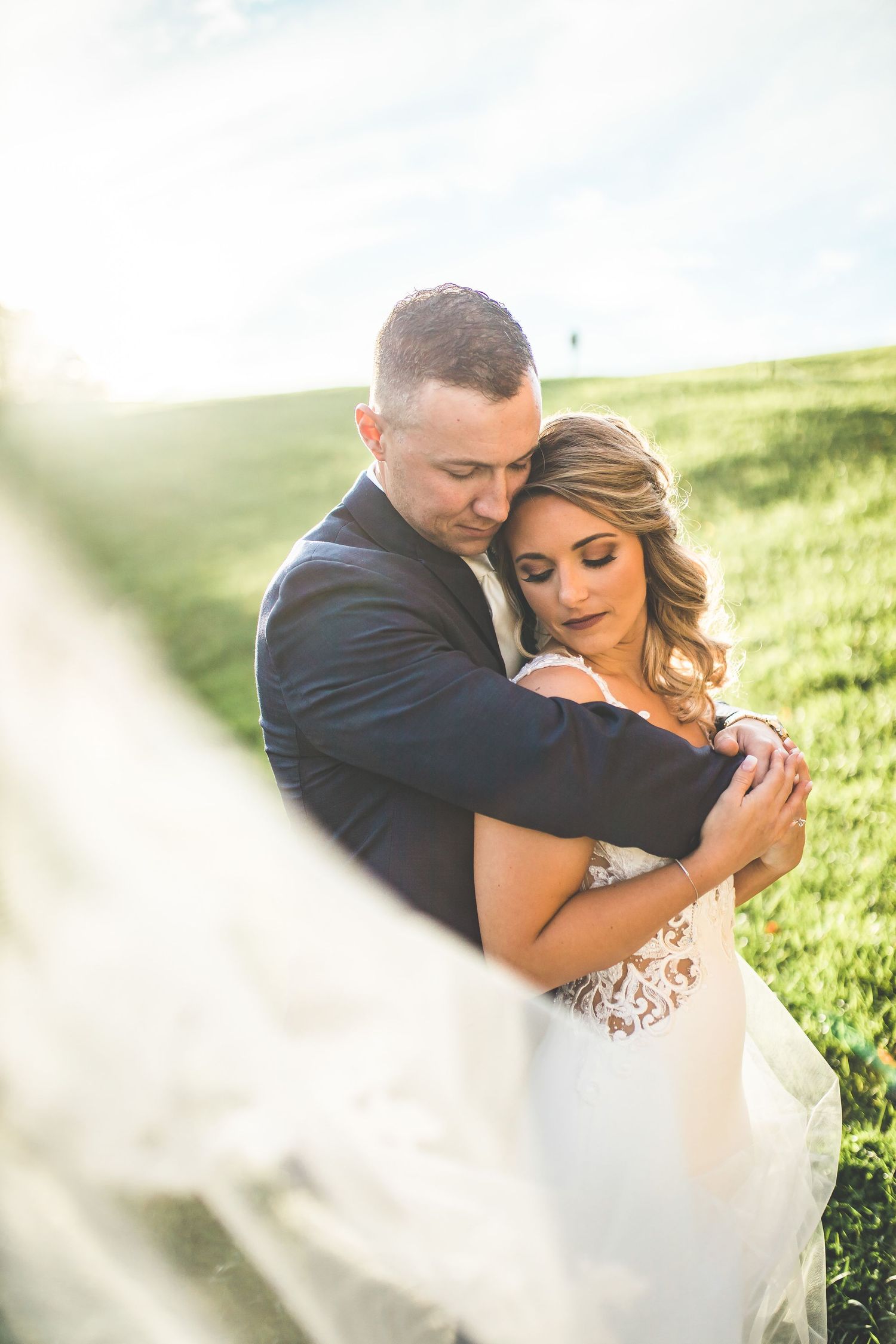 Romantic outdoor wedding photography session in a sunlit meadow.