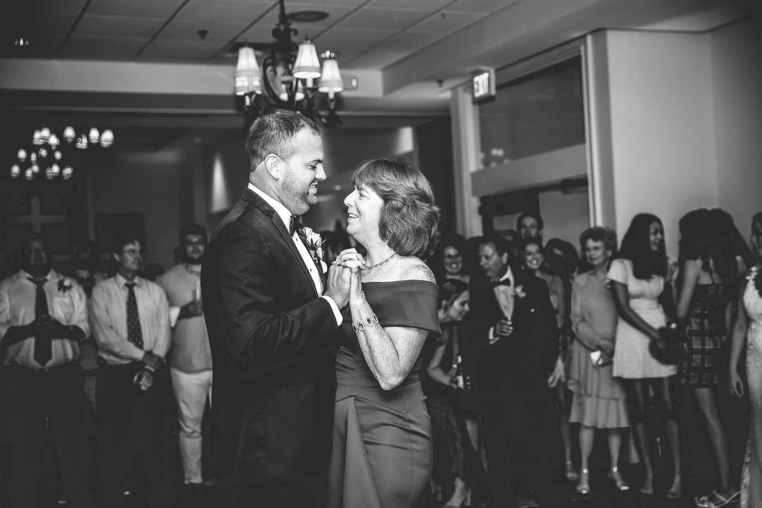 Black and white photo of wedding guests dancing and celebrating on the dance floor.
