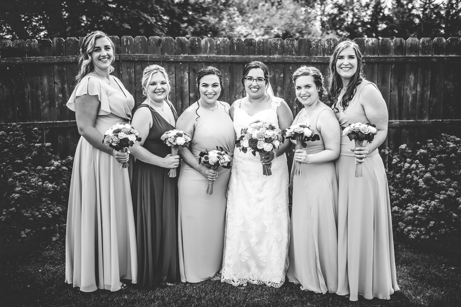 Wedding party members in navy and pink attire pose for formal black and white portraits.